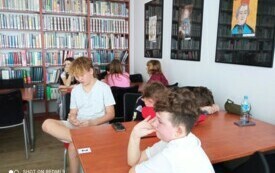 Zdjęcie przedstawia uczni&oacute;w siedzących na tle książek.