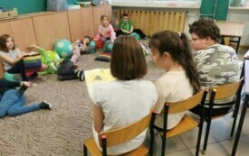 Zdjęcie przedstawia uczni&oacute;w, kt&oacute;rzy czytają innym.