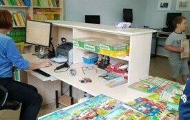 Na zdjęciu uczeń wypożycza książkę w bibliotece.